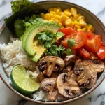 Close-up view of a vibrant vegan bowl with colorful ingredients, including mushrooms, avocado, and corn.