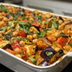 ['Close-up side view of a creamy chickpea bake topped with melted cheese and colorful diced vegetables.', 'A deliciously creamy chickpea bake, showcasing a medley of diced carrots, aubergine, courgette, and red pepper.', 'Side view of a golden-brown creamy chickpea bake, featuring layers of vegetables and cheese.', 'Close-up of a golden creamy chickpea bake with visible chunks of vegetables and a cheesy topping.']
