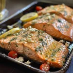 ['Juicy baked salmon fillets with cherry tomatoes and garnish.', 'Close-up of Easy Baked Greek Salmon with lemon slices and olives.', 'Side view of succulent salmon topped with fresh dill and feta cheese.', 'Delicious, golden salmon fillets garnished with herbs and vegetables.']