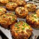 ['Juicy ground beef muffins displayed with a side view, showcasing their golden tops and rich texture.', 'Close-up image of Easy Ground Beef Muffins, highlighting their moist interior and sprinkled toppings.', 'Side view of savory ground beef muffins on a plate, featuring visible carrots and green onions.', "Appetizing ground beef muffins with a golden crust, view capturing the muffin's height and ingredients."]