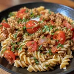 ['Close-up of a bowl of ground turkey pasta with melted cheese on top.', 'Side view of a serving of ground turkey pasta, showcasing the sauce and ingredients.', 'Detailed image of ground turkey pasta with herbs and cheese, presented in a bowl.', 'A vibrant dish of ground turkey pasta, highlighting the textures and colors of the ingredients.']