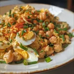 ['A close-up view of a vibrant chickpea egg salad with green onions and chives.', 'Side view of a creamy high protein chickpea egg salad placed in a bowl.', 'A textured dish featuring hard-boiled eggs and chickpeas garnished with chives.', 'A colorful salad mixture in a bowl highlighting chickpeas and diced green onions.']