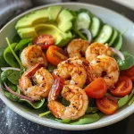 ['Close-up view of a vibrant High-protein Shrimp Salad with shrimp, mixed greens, and vegetables.', 'A colorful Shrimp Salad featuring avocado, cherry tomatoes, and cucumber, presented in a bowl.', 'Side view of a delicious shrimp salad garnished with red onion and sprinkled spices.', 'Fresh High-protein Shrimp Salad showcasing juicy shrimp and assorted greens in a light dressing.']