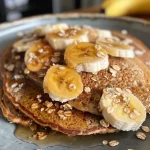 ['Close-up of golden-brown lentil protein pancakes stacked on a plate.', 'Side view of delicious lentil protein pancakes, drizzled with syrup.', 'Juicy lentil protein pancakes with a soft texture, ready to eat.', 'A plate of lentil protein pancakes topped with fresh banana slices.']