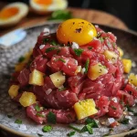 ['Close-up of beautifully plated Steak Tartare with golden fries.', 'Artistic presentation of raw Steak Tartare garnished with herbs and served with crispy fries.', 'Fresh Steak Tartare served in a bowl, accompanied by perfectly fried potato strips.', 'Side view of a gourmet Steak Tartare dish featuring vibrant colors and textures.']