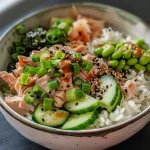 ['A close-up side view of a Tuna Mayo Rice Bowl with vibrant ingredients.', 'A detailed look at a Tuna Mayo Rice Bowl featuring layers of rice, tuna, and vegetables.', 'A Tuna Mayo Rice Bowl captured from a side angle showcasing fresh toppings.', 'A colorful Tuna Mayo Rice Bowl highlighting avocado, cucumber, and sesame seeds.']