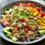 ['Close-up view of a colorful tuna salad with various fresh vegetables and hard-boiled eggs.', 'Side angle of a vibrant tuna salad featuring diced cucumbers, bell peppers, and onions.', 'Juicy tuna salad prepared with mayonnaise, garnished with slices of red onion and celery.', 'Freshly made tuna salad displaying a mix of vegetables and eggs, served in a bowl.']