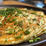 ['A close-up side view of a Turkish herb omelet pancake, showcasing its golden-brown texture.', 'Juicy Turkish herb omelet pancake displayed on a plate, highlighting fresh green herbs embedded within.', 'A vibrant Turkish omelet pancake with a crispy edge and a soft, fluffy center, garnished with herbs.', 'Side view of a traditional Black Sea kaygana, emphasizing its rich texture and colorful ingredients.']