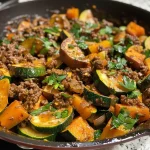 ['Close-up view of a juicy Ground Beef Zucchini Sweet Potato Skillet.', 'A colorful skillet filled with ground beef, zucchini, sweet potato, and spinach.', 'Side view of a vibrant dish featuring ground beef and diced sweet potatoes.', 'Savory skillet meal with ground beef, zucchini slices, and fresh parsley garnish.']