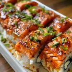 ['Close-up view of a delicious Spicy Salmon Sushi Bake on a plate.', 'Side angle of a Spicy Salmon Sushi Bake, showcasing its ingredients and texture.', 'Juicy Spicy Salmon Sushi Bake with a golden top, garnished with green onions.', 'Detailed view of a creamy Spicy Salmon Sushi Bake with roasted seaweed snacks.']