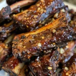 ['Juicy five spice BBQ beef ribs glistening with sauce.', 'Side view of tender beef short ribs coated in a savory glaze.', 'Close-up of five spice BBQ ribs with a caramelized exterior.', 'Delicious beef ribs with a rich, dark BBQ sauce.']