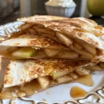 Close-up view of golden apple cinnamon breakfast quesadillas with melted cheese.