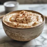 Close-up view of a creamy chai latte dip served with sliced apples.