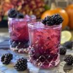 Close-up view of a Halloween mocktail with blackberries and butterfly pea tea.