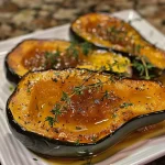 Close-up of honey-glazed acorn squash halved and topped with creamy goat cheese and cranberry drizzle.