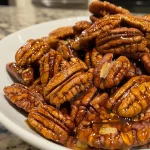 Close-up of glossy maple glazed pecans with a buttery sheen.
