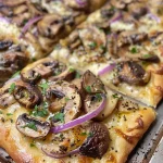 Close-up view of Mushroom Fontina Flatbread topped with crispy sage leaves.