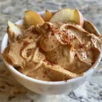 A close-up side view of sliced pear with a creamy peanut butter yogurt dip.