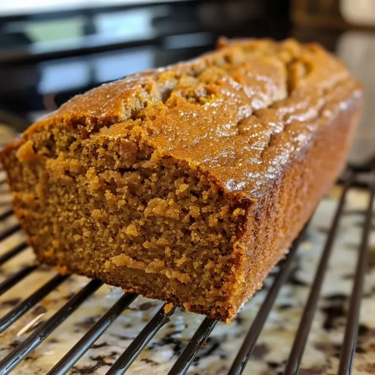 Aunt Lynne’s Pumpkin Bread: A Cozy Slice of Fall A close-up side view of a slice of moist pumpkin bread on a wooden surface.