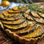 Close-up view of a sliced Roasted Acorn Squash Tart showcasing a golden crust and vibrant filling.