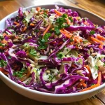 Close-up of a colorful slaw featuring purple and green cabbage, carrots, and seeds.