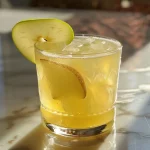 Close-up of a sparkling pear and ginger cocktail in a glass with bubbles rising.