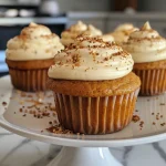 A close-up side view of healthy pumpkin cupcakes topped with cream cheese frosting.