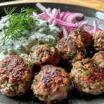 Close-up view of juicy walnut meatballs served with a creamy tzatziki sauce.